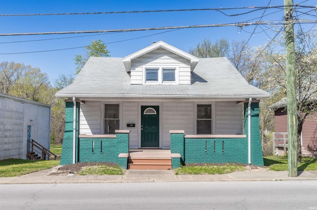 bungalow-style home featuring brick siding and covered porch