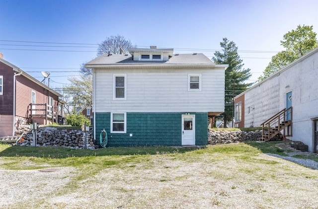 rear view of house with a lawn and stairway