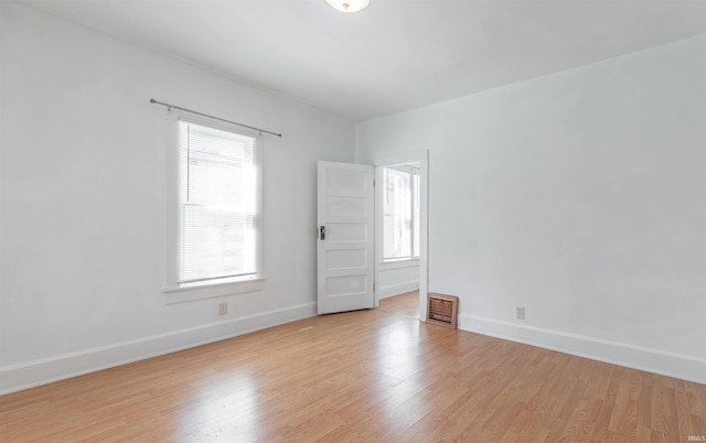 spare room with baseboards, a wealth of natural light, and light wood-style floors