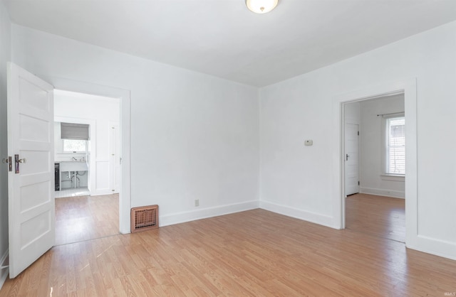 spare room featuring visible vents, light wood finished floors, and baseboards