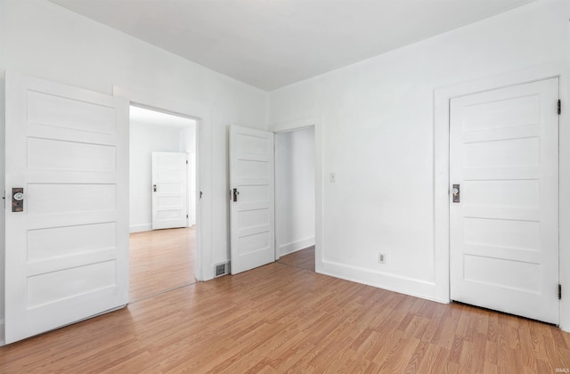 empty room with baseboards, light wood finished floors, and visible vents