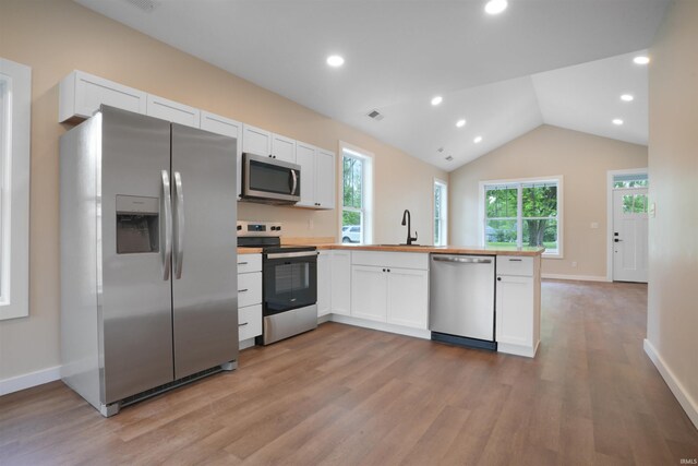 kitchen featuring appliances with stainless steel finishes, a peninsula, white cabinetry, light wood-type flooring, and visible vents