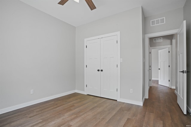 unfurnished bedroom with visible vents, baseboards, wood finished floors, and a closet