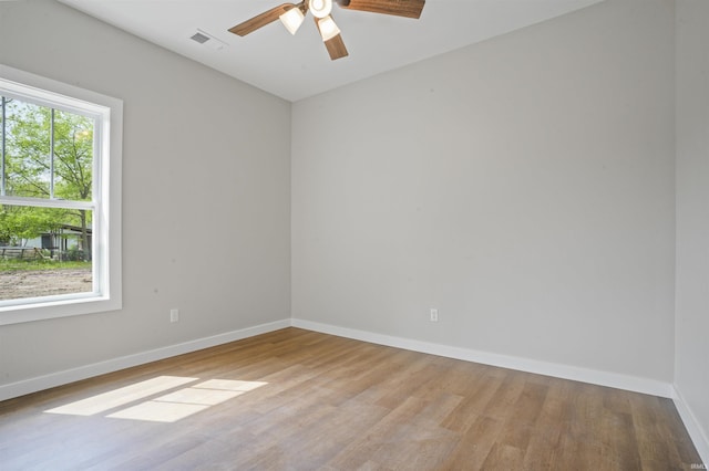 unfurnished room featuring baseboards, a ceiling fan, wood finished floors, and visible vents