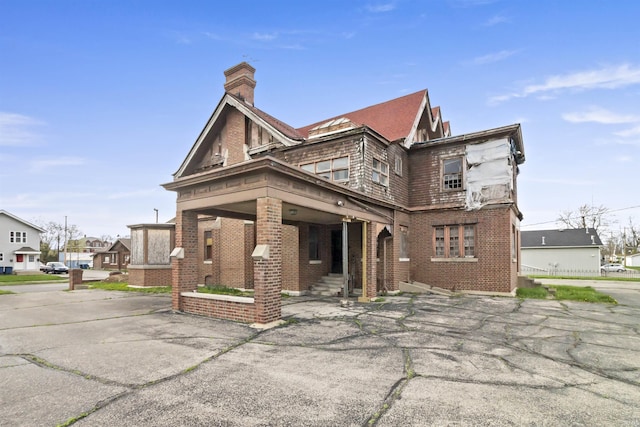 view of front of home featuring a chimney and brick siding