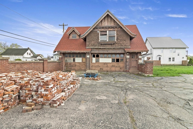 rear view of property with fence and stone siding