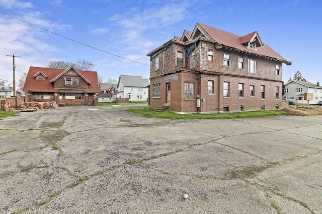 view of side of home with uncovered parking, brick siding, and a residential view
