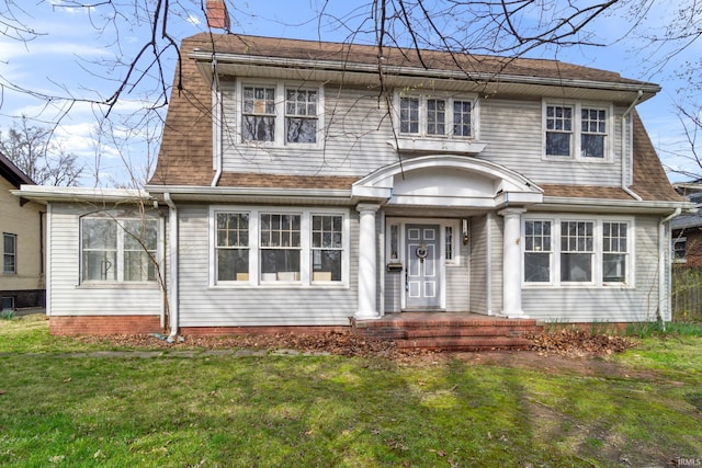view of front of house featuring a chimney, a front lawn, and roof with shingles