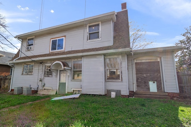 view of front of property featuring cooling unit, a chimney, a front lawn, and fence