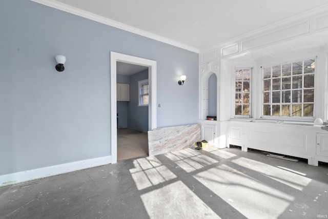 spare room with concrete floors, ornamental molding, and baseboards
