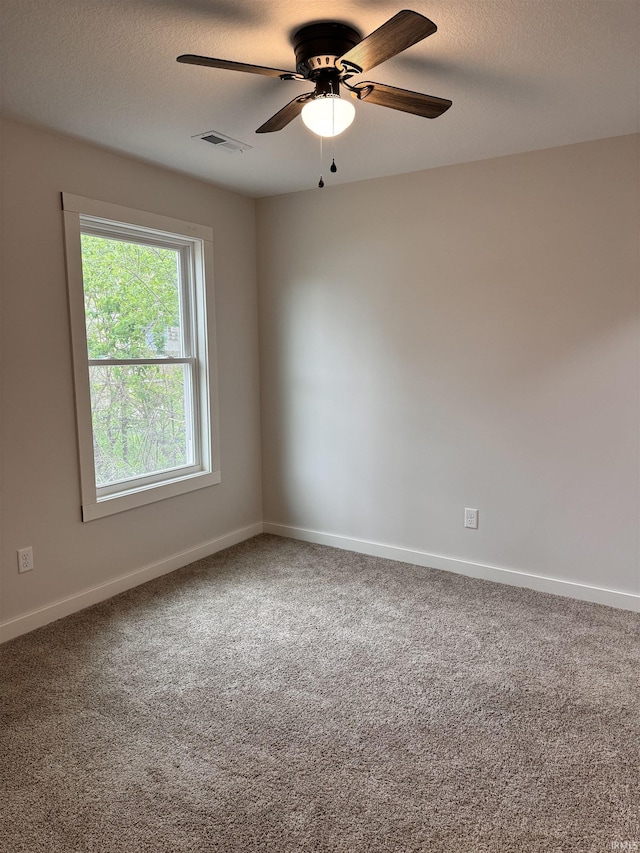 spare room featuring baseboards, visible vents, a ceiling fan, and carpet