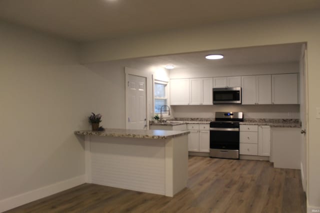 320 W Ritter St, Ellettsville, IN 47429 - kitchen featuring stainless steel appliances, baseboards, a peninsula, white cabinetry, and dark wood-type flooring