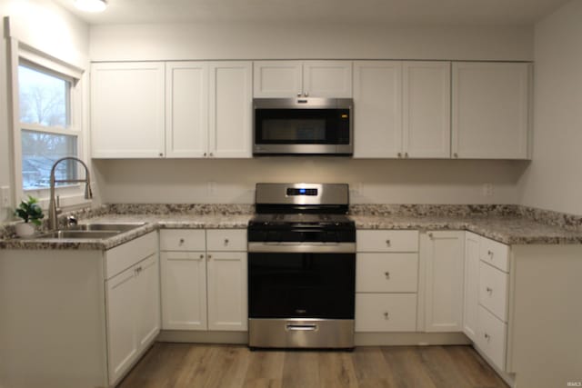 320 W Ritter St, Ellettsville, IN 47429 - kitchen featuring white cabinets, appliances with stainless steel finishes, a sink, and light wood-style flooring
