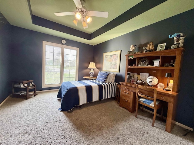 bedroom with baseboards, carpet floors, ceiling fan, and a tray ceiling