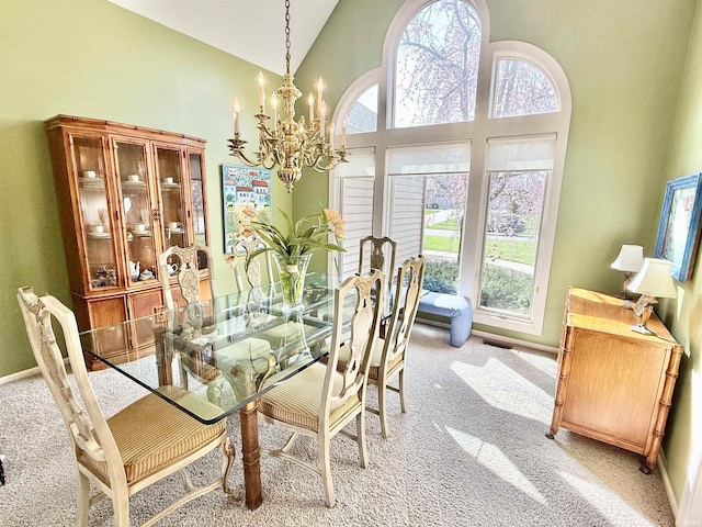 dining area featuring baseboards, a towering ceiling, a chandelier, and light colored carpet