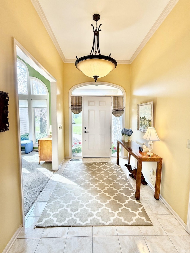 tiled entryway with crown molding and baseboards