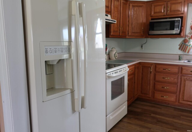 12176 E 350 N, Loogootee, IN 47553 - kitchen featuring dark wood-style floors, under cabinet range hood, light countertops, white appliances, and brown cabinetry