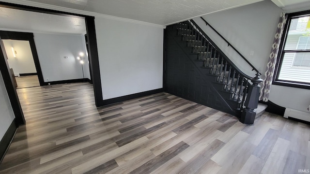 unfurnished living room with baseboards, crown molding, wood finished floors, and stairs