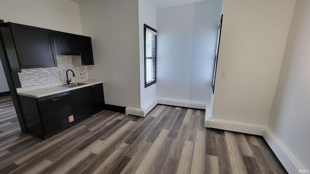 kitchen with light countertops, dark cabinetry, a sink, black dishwasher, and tasteful backsplash