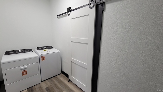 laundry room with a barn door, light wood finished floors, laundry area, and separate washer and dryer