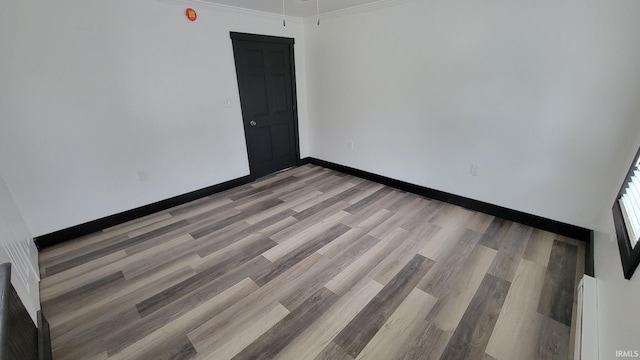 unfurnished room featuring light wood-style flooring, crown molding, and baseboards