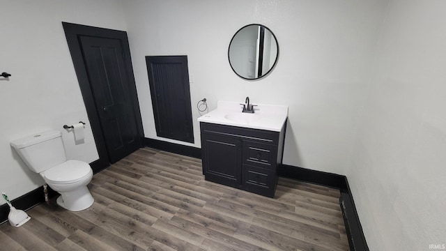 half bathroom featuring wood finished floors, vanity, and toilet