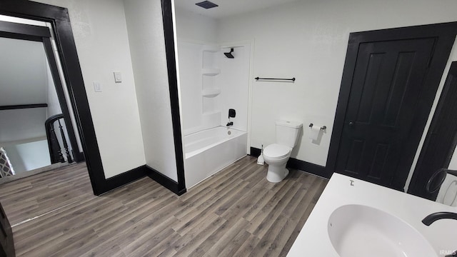 full bath with baseboards, wood finished floors, a sink, and toilet