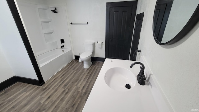 bathroom with toilet, shower / bathtub combination, baseboards, wood finished floors, and vanity