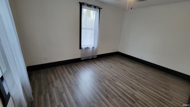 empty room featuring baseboards, a ceiling fan, and dark wood-style floors