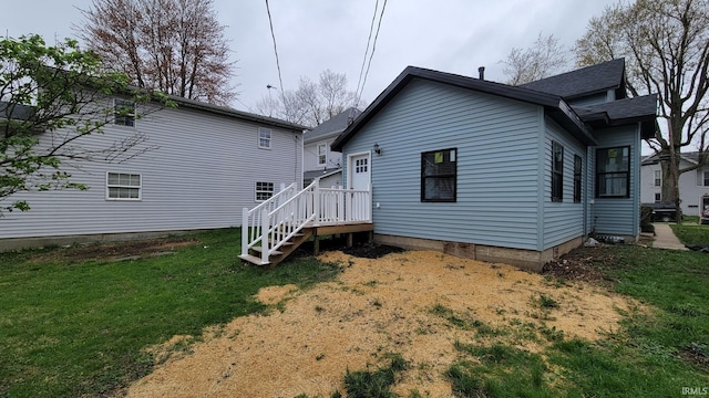 rear view of house featuring a lawn and roof with shingles