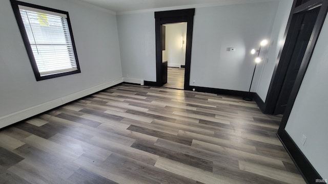spare room with baseboards, wood finished floors, and ornamental molding