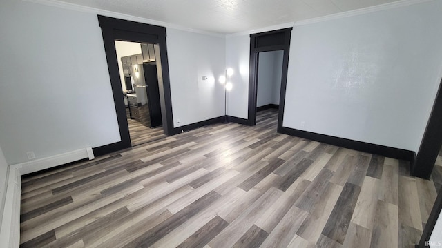 empty room featuring baseboards, ornamental molding, wood finished floors, and visible vents