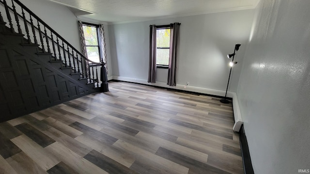 interior space featuring stairs, crown molding, wood finished floors, and baseboards
