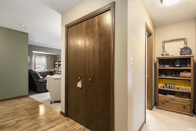 corridor featuring baseboards and light wood-type flooring