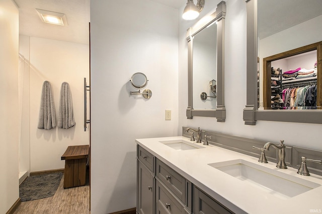 full bathroom with double vanity, wood finished floors, baseboards, and a sink
