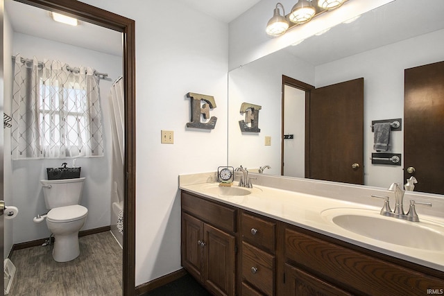 bathroom with wood finished floors, a sink, double vanity, and toilet