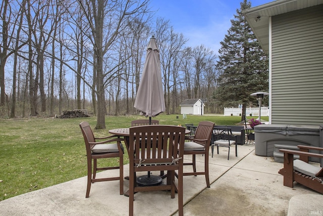 view of patio featuring outdoor dining area, a hot tub, an outbuilding, and a storage unit