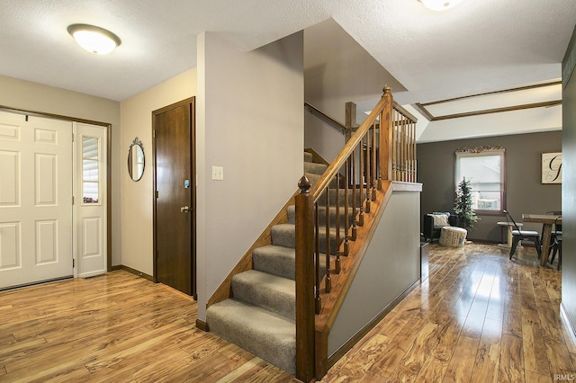 foyer entrance with wood finished floors, baseboards, and stairway