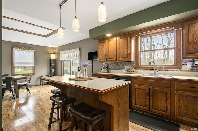 kitchen featuring a center island, tasteful backsplash, a sink, light wood-style floors, and light countertops