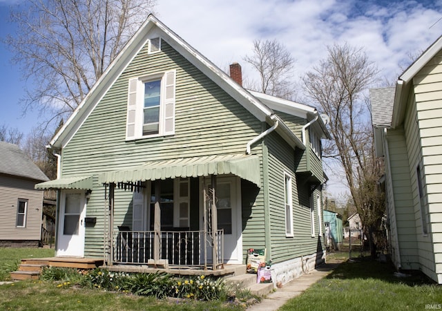 rear view of property featuring a chimney and covered porch