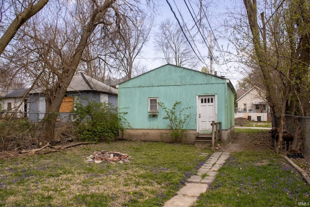 view of outdoor structure with entry steps, an outdoor fire pit, and fence