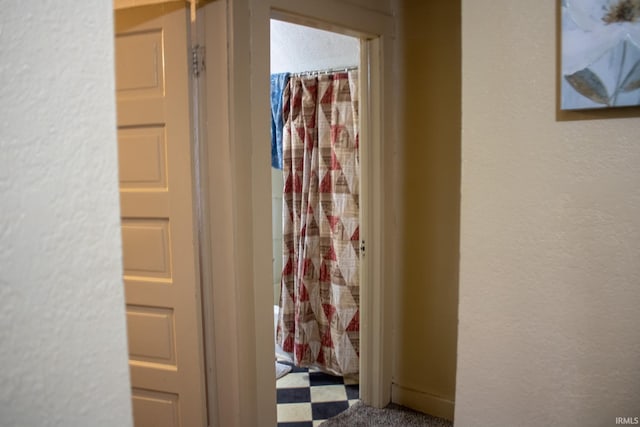 hallway with a textured wall and tile patterned floors