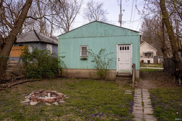 view of outdoor structure featuring fence, entry steps, and an outdoor fire pit