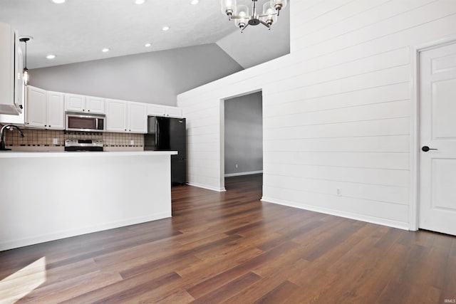 kitchen featuring a peninsula, an inviting chandelier, decorative backsplash, high vaulted ceiling, and appliances with stainless steel finishes