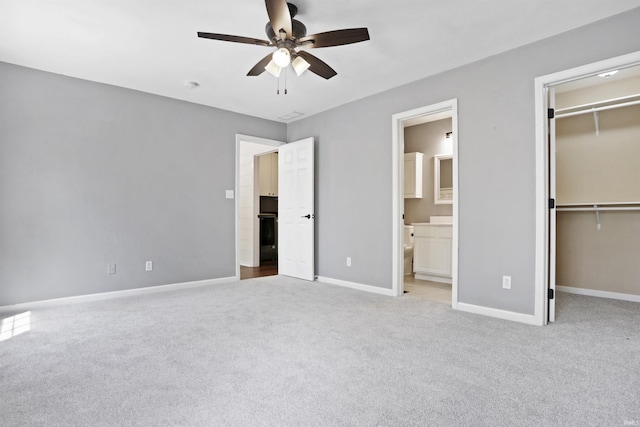 unfurnished bedroom with a walk in closet, carpet floors, a closet, and baseboards