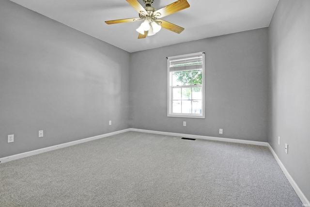 carpeted empty room with visible vents, baseboards, and ceiling fan