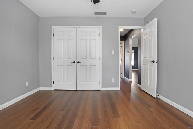 unfurnished bedroom with baseboards, visible vents, and dark wood finished floors
