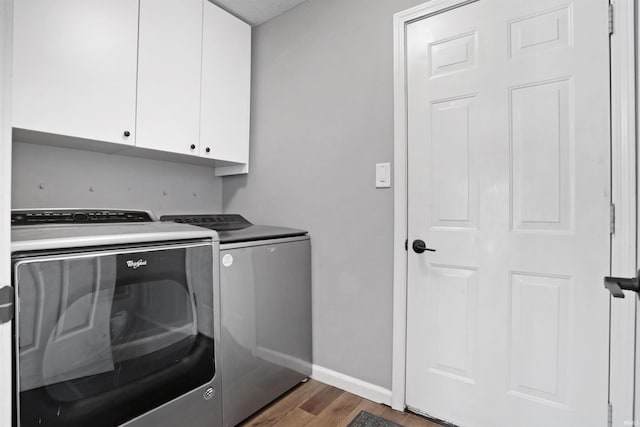 laundry room featuring baseboards, cabinet space, wood finished floors, and independent washer and dryer