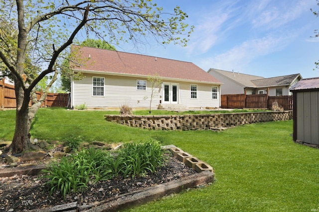 back of property featuring a fenced backyard, a shed, a lawn, and french doors