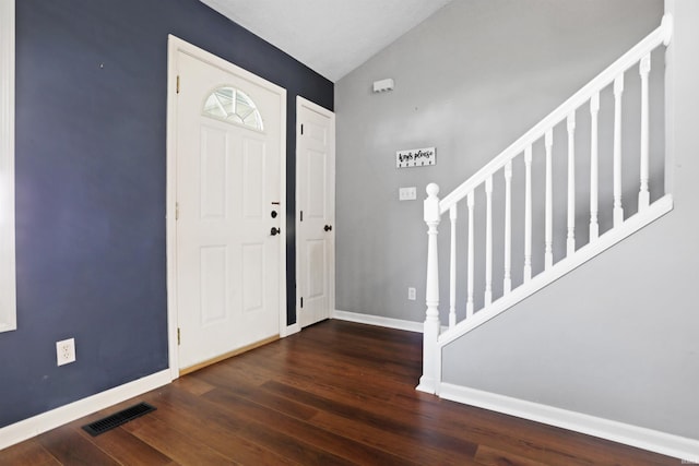 entryway with stairway, vaulted ceiling, wood finished floors, baseboards, and visible vents